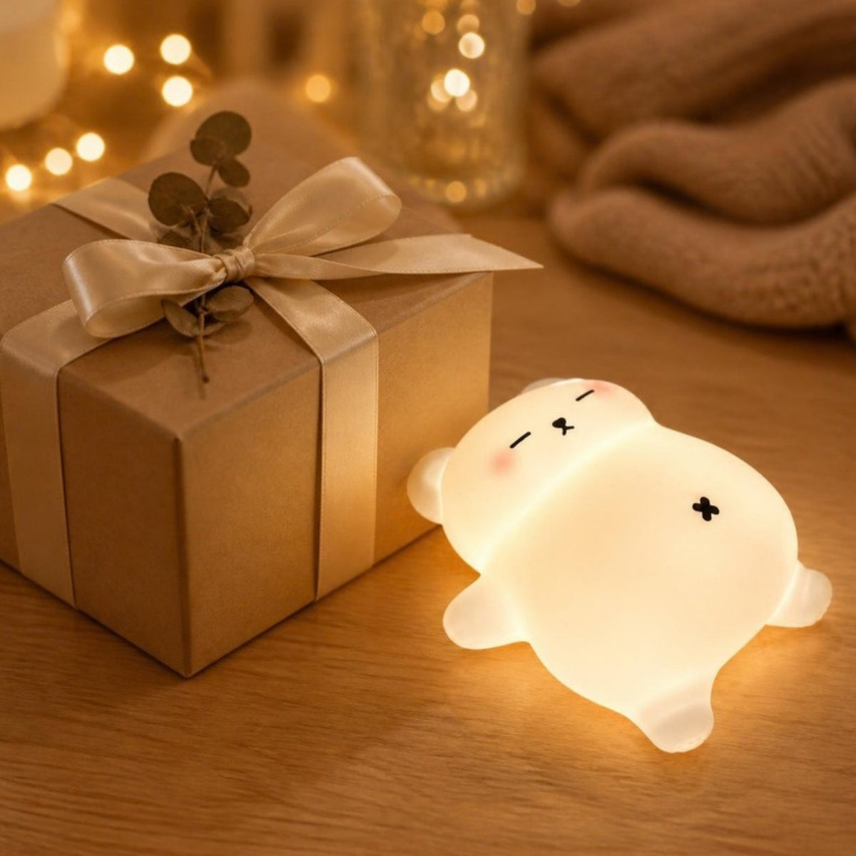 Veilleuse ourson Mimounou à côté d'un paquet cadeau en papier kraft