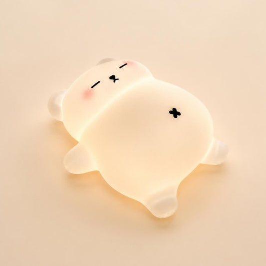 Veilleuse ourson Mimounou en silicone blanc, allumée, sur fond crème